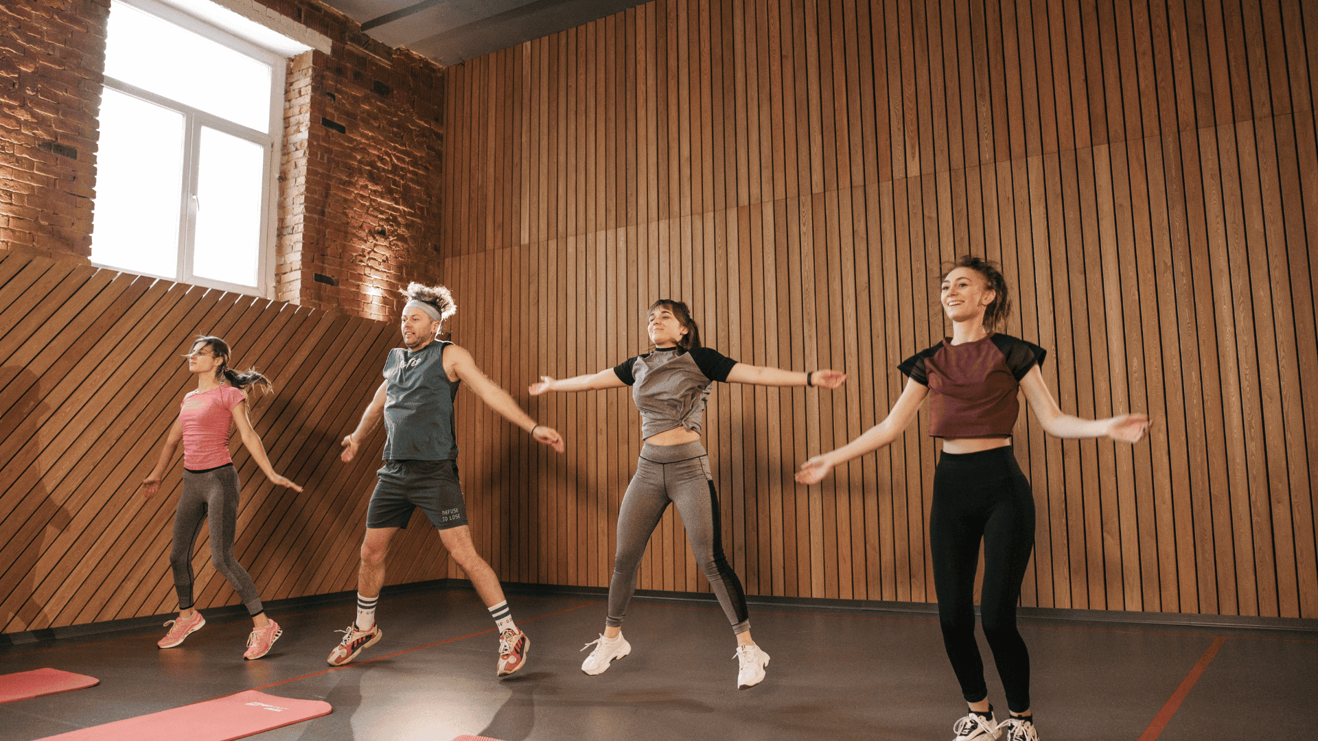 Group of people doing jumping jacks together in a fitness studio, mid-exercise during a 30-rep set.