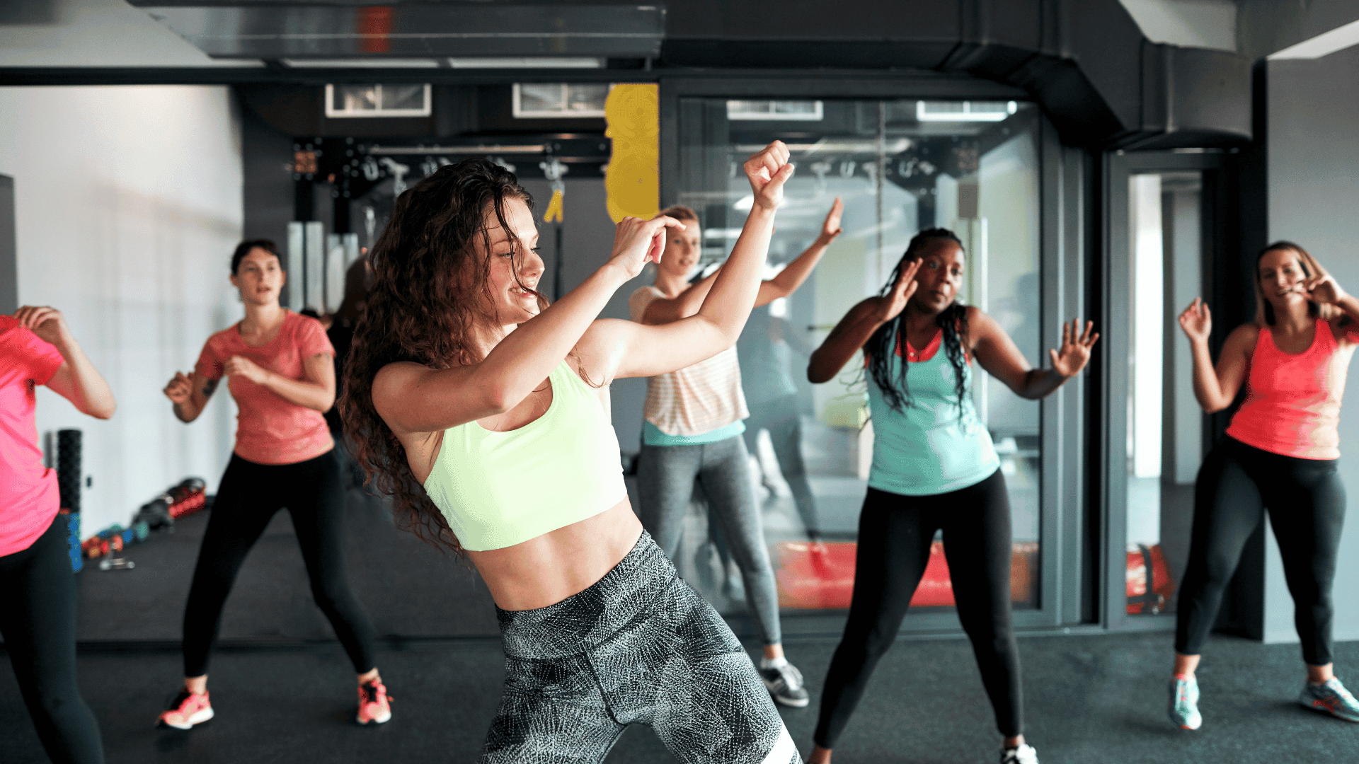 Group of women enjoying a high-energy dance-party cardio workout in a fitness studio.