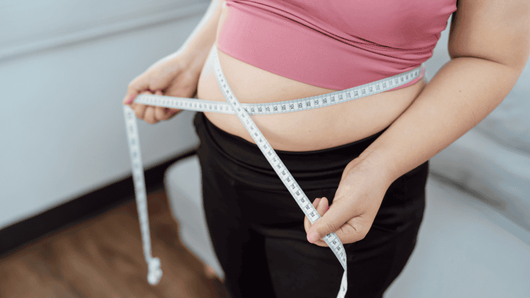 A lady measuring her belly with a measuring tape