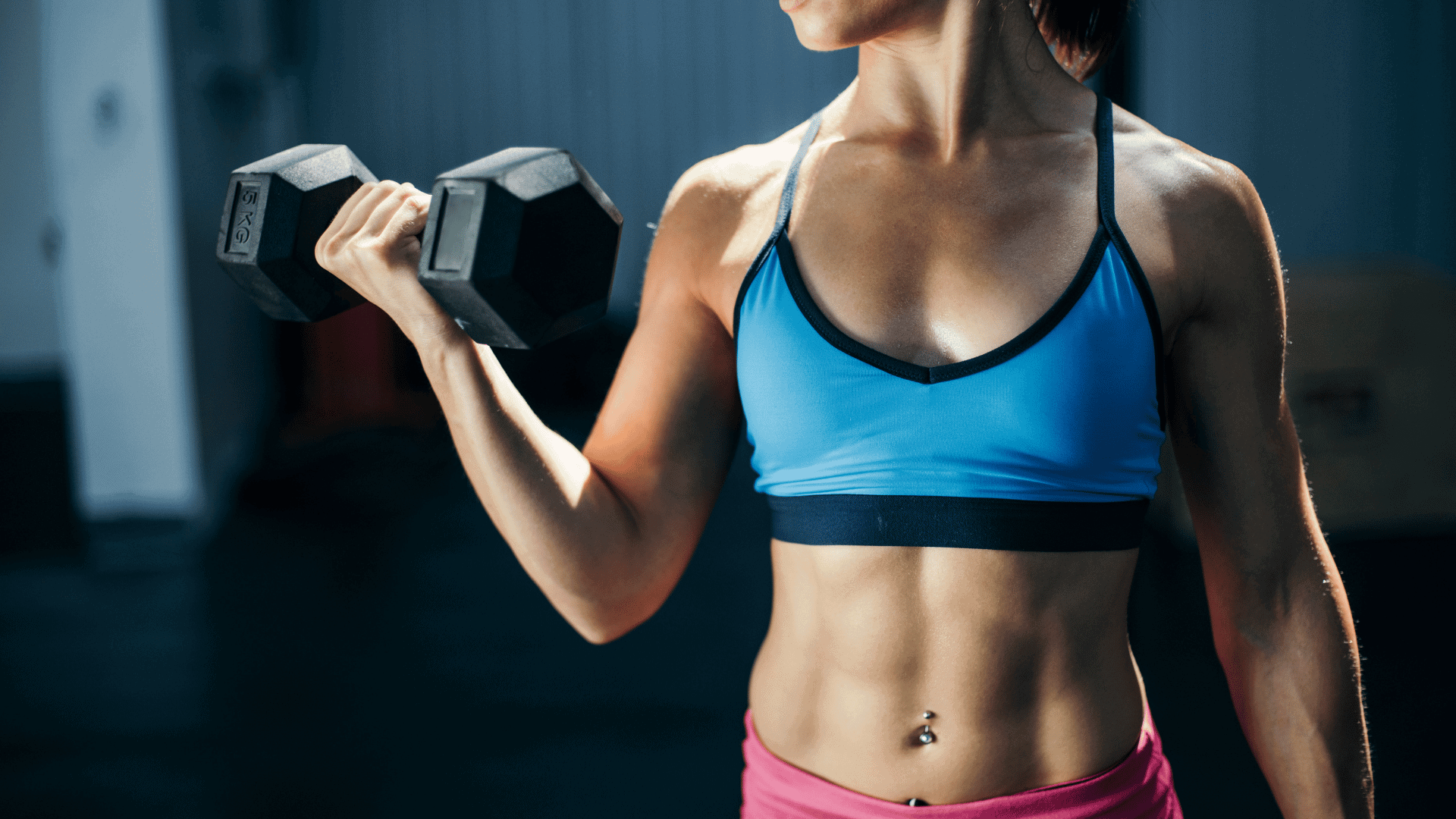 Woman lifting a dumbbell for a bicep curl in the gym.