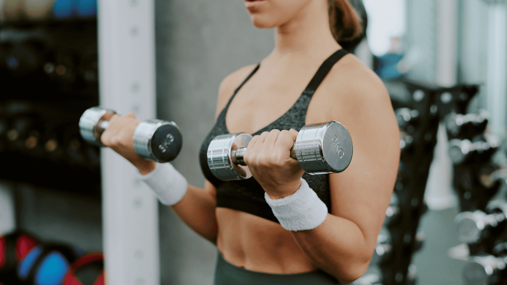 Woman curling dumbbells at the gym with focus on form and arm position.