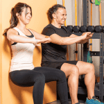 Man and Woman Doing Squats While Leaning on a Wall