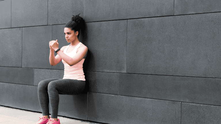 Athlete doing wall squat on city street