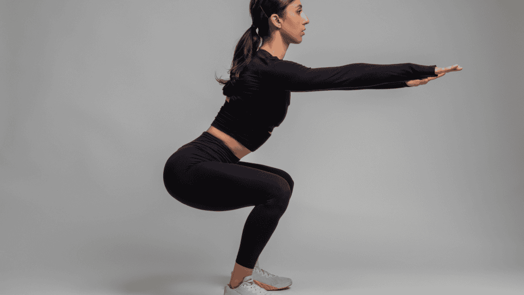 Side View of Girl Doing Squats on Grey Background