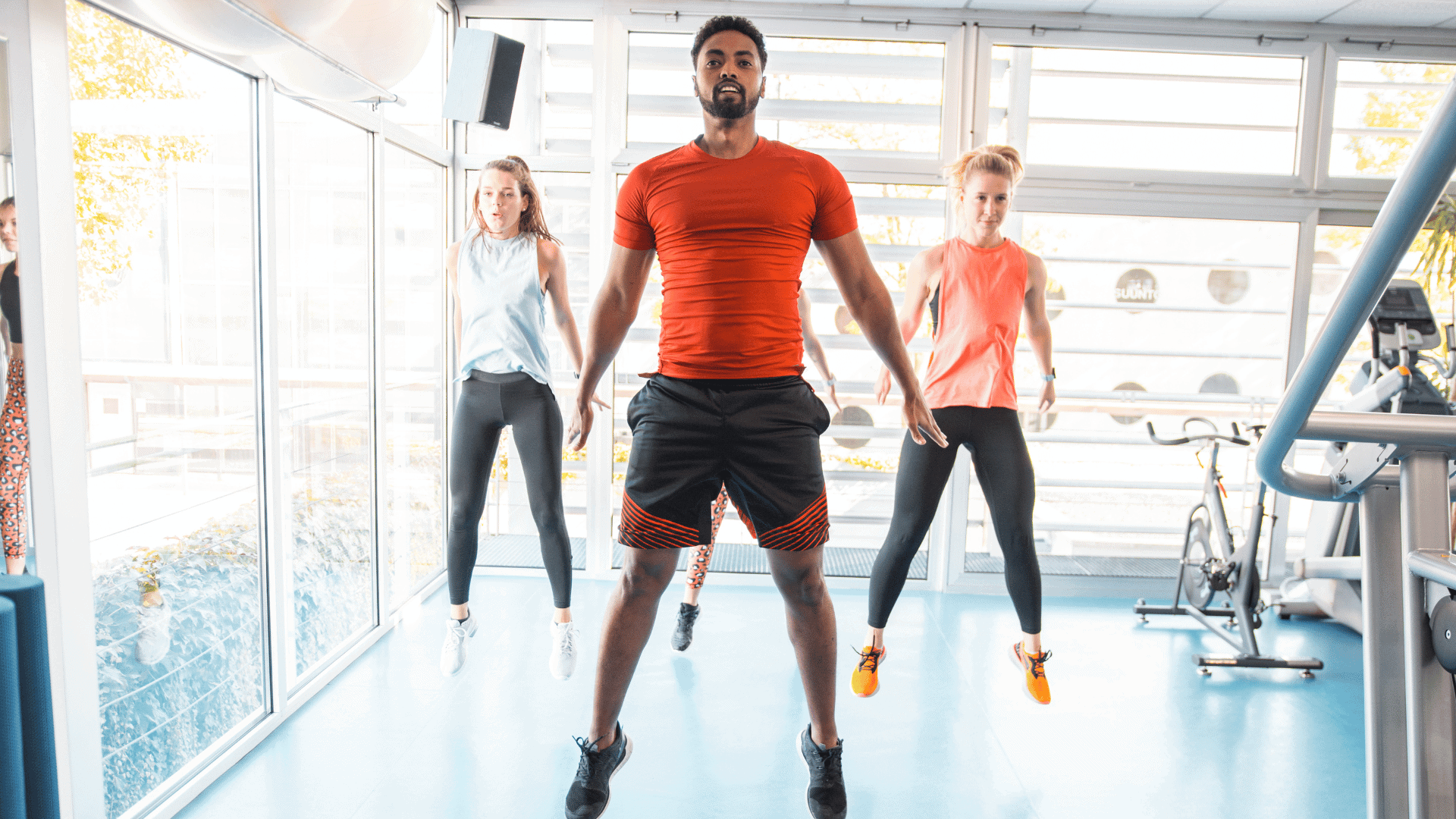 Small group of people doing burpee exercise in the gym