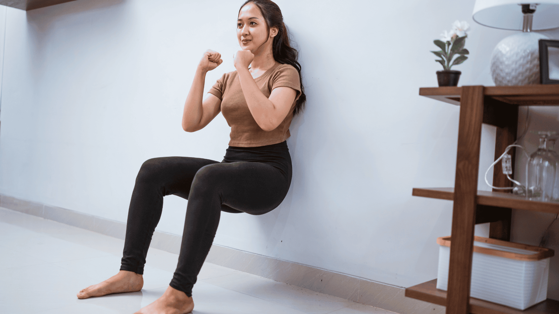 Woman Squating against the Wall at Home Woman doing wall squats at home