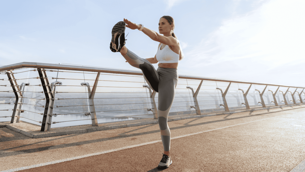 Young lady doing leg swing on foot bridge