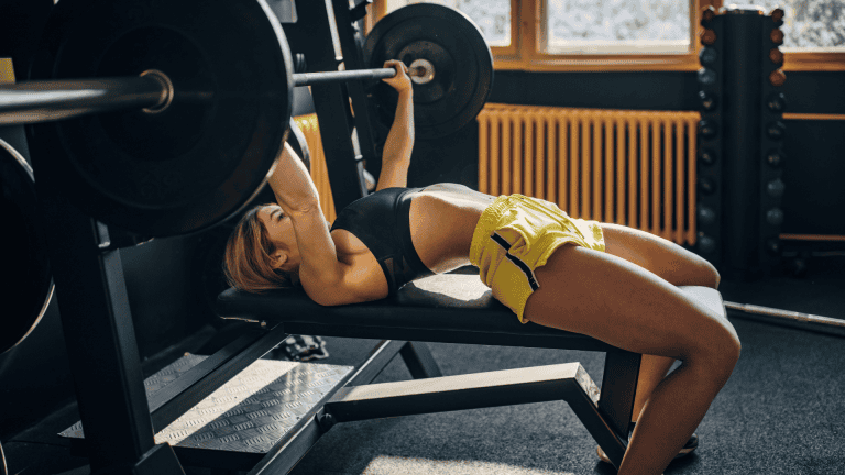 A lady doing a barbell bench press