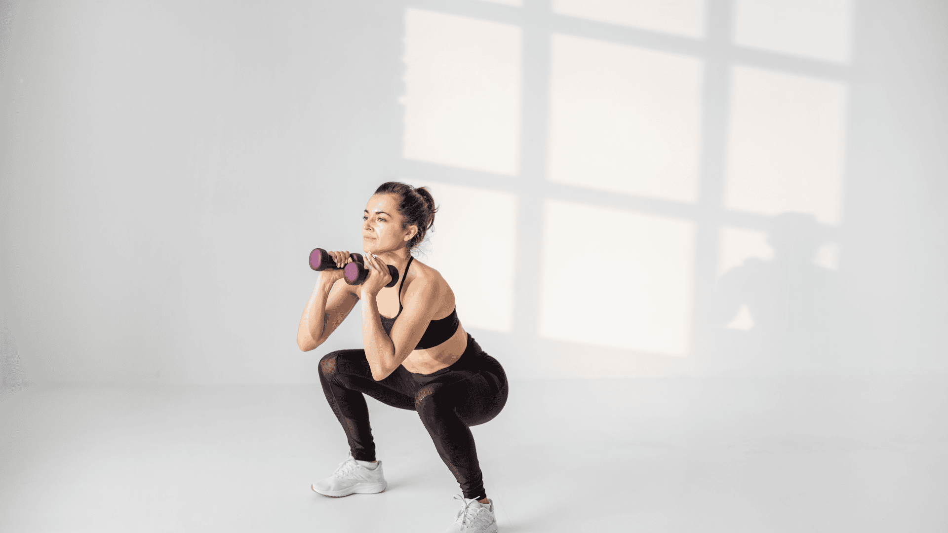 A lady doing squat to press with dumbbells at home