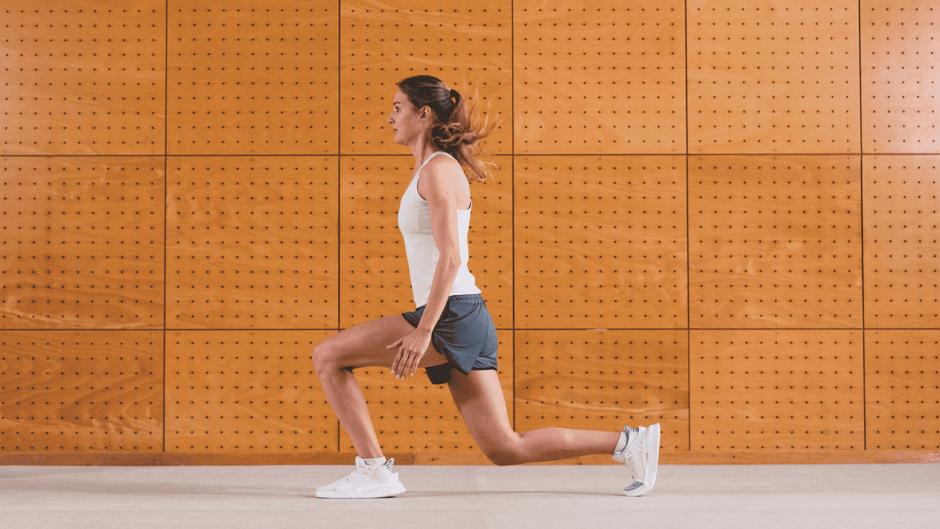 A lady doing static lunges in an orange background A lady doing static lunges in an orange background