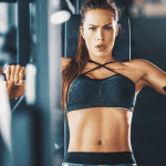 Focused woman in athletic wear performing a strength training exercise on a chest press machine at the gym, showcasing intensity and determination as part of a weekly gym workout plan for women.