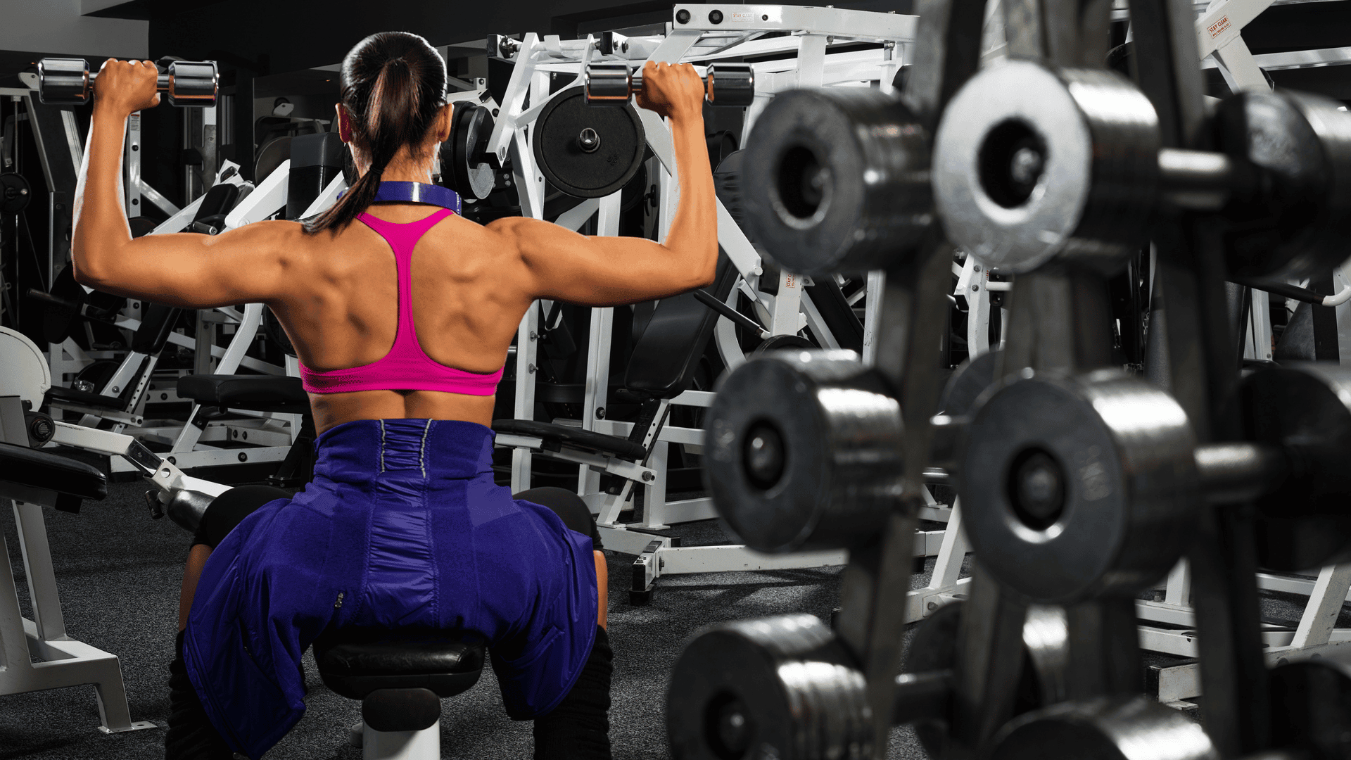 Woman lifting dumbbells at the gym for upper body sculpting.