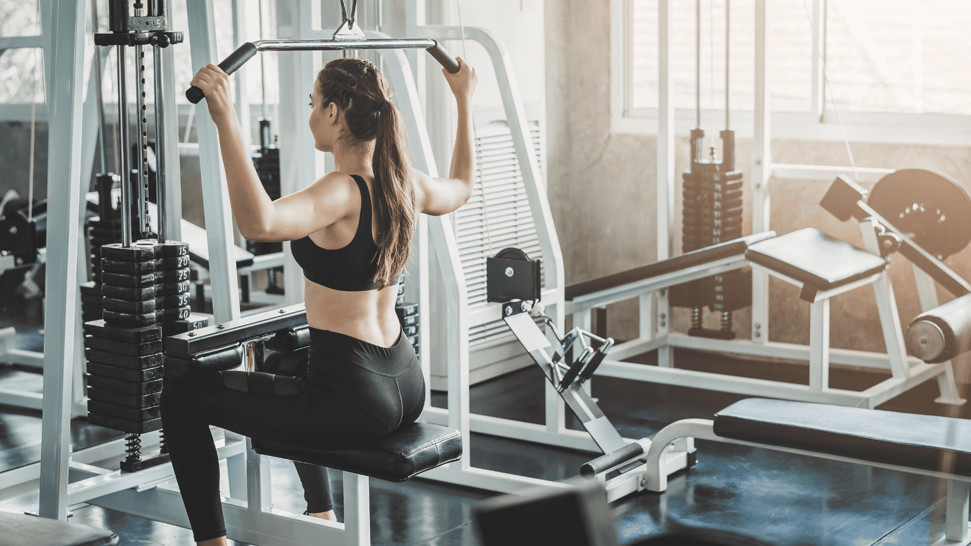 woman doing lat pull pull down exercise in fitness gym