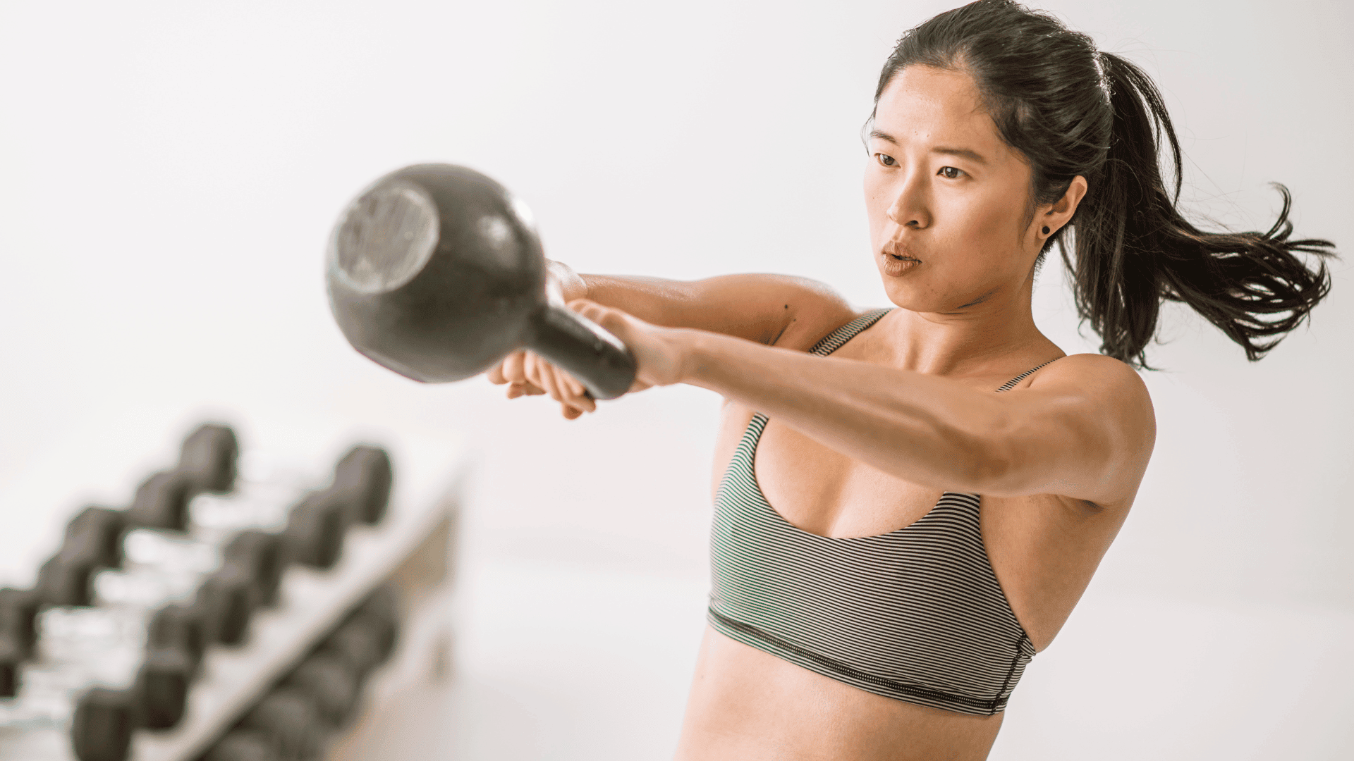 A woman wearing fitwear doing kettlebell swings