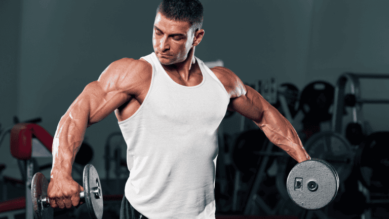 Muscular man performing shoulder raises with dumbbells in a gym.