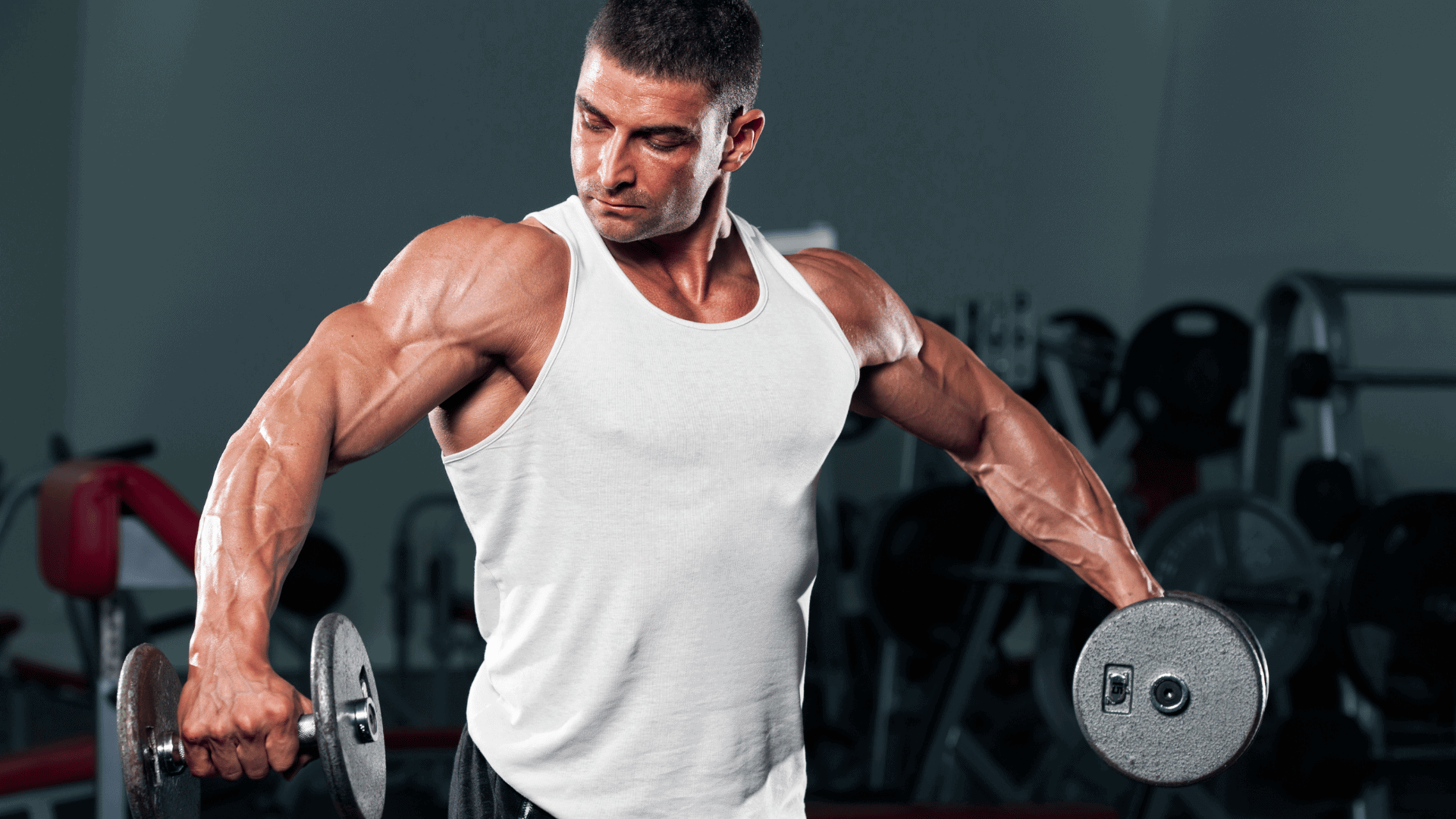 Muscular man performing shoulder raises with dumbbells in a gym.