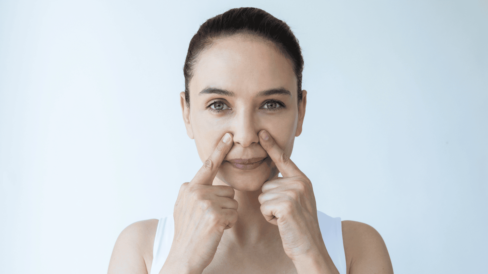 Woman pressing both index fingers on smile lines for a face yoga exercise.